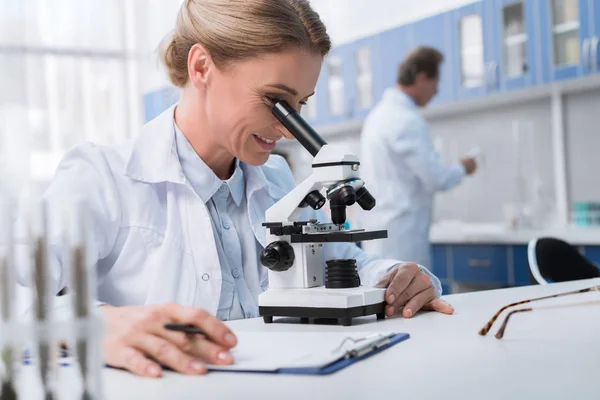 Químico trabajando con microscopio - foto de stock