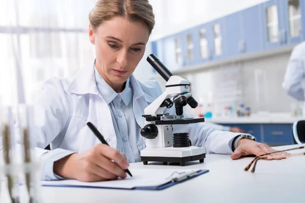 Lab technician taking notes — Stock Photo