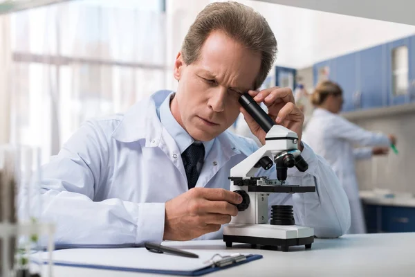 Chemist working with microscope — Stock Photo