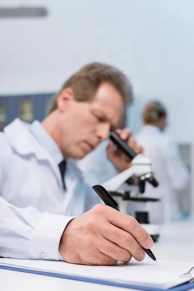 Técnico de laboratorio tomando notas - foto de stock