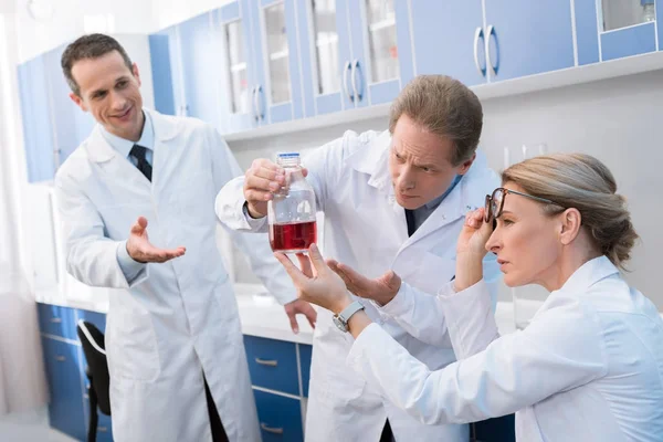 Scientists examining flask with reagent — Stock Photo