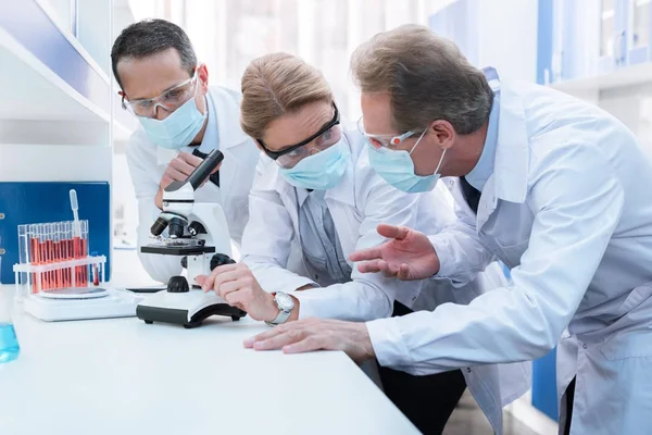 Chemists using microscope and discussing — Stock Photo