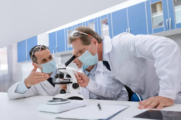 Científicos que trabajan con microscopio - foto de stock