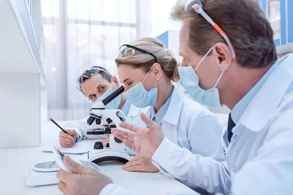 Científicos haciendo análisis de microscopio - foto de stock