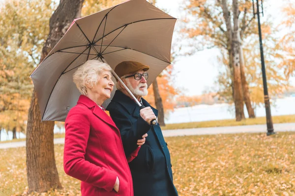 Coppia senior con ombrellone nel parco — Foto stock