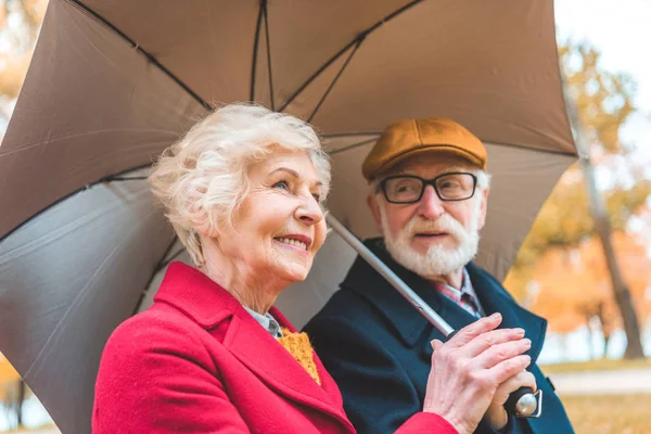 Старшая пара с зонтиком — стоковое фото