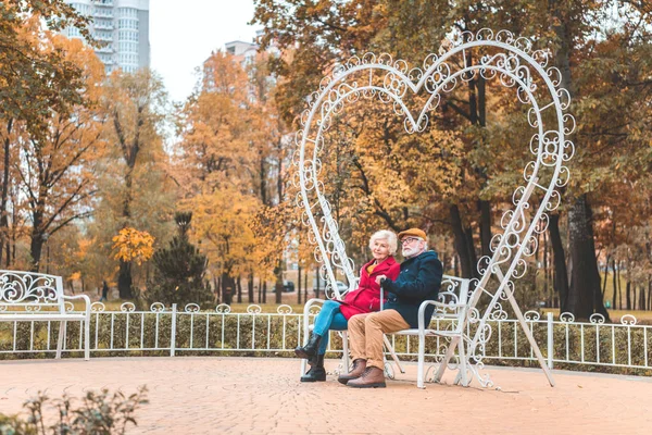 Heart shaped bench in autumn park — Stock Photo