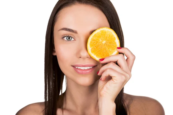 Woman covering eye with slice of orange — Stock Photo