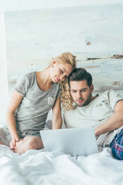 Pareja usando portátil en la cama - foto de stock