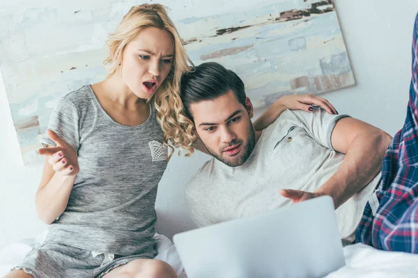 Pareja usando portátil en la cama - foto de stock