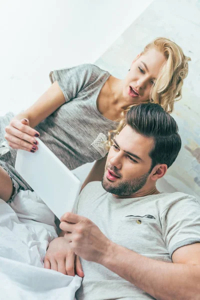 Pareja con tableta digital en la cama - foto de stock