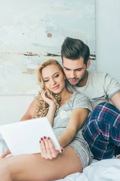 Pareja con tableta digital en la cama - foto de stock