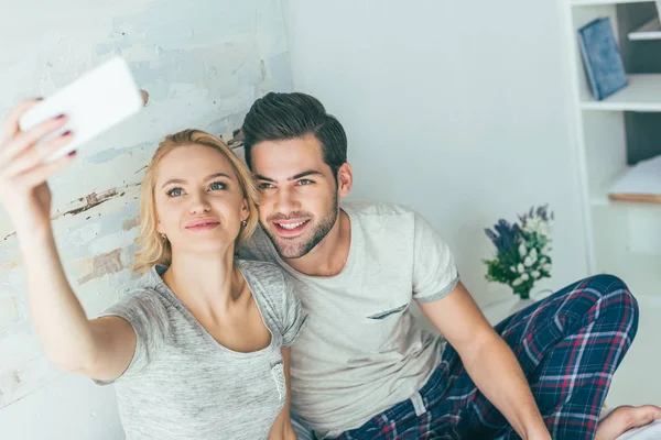 Casal usando Smartphone na cama — Fotografia de Stock