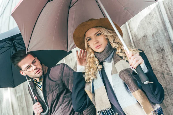 Stilvolles junges Paar mit Regenschirmen — Stockfoto