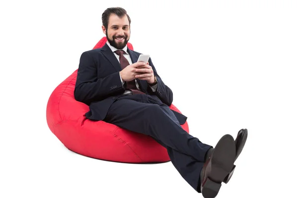 Homme d'affaires avec smartphone sur chaise de sac de haricot — Photo de stock