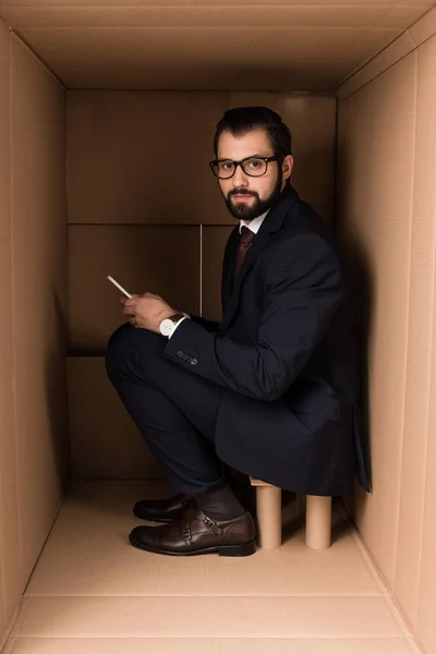 Businessman using smartphone in box — Stock Photo