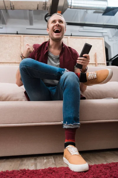 Excité beau homme regardant la télévision à la maison — Photo de stock