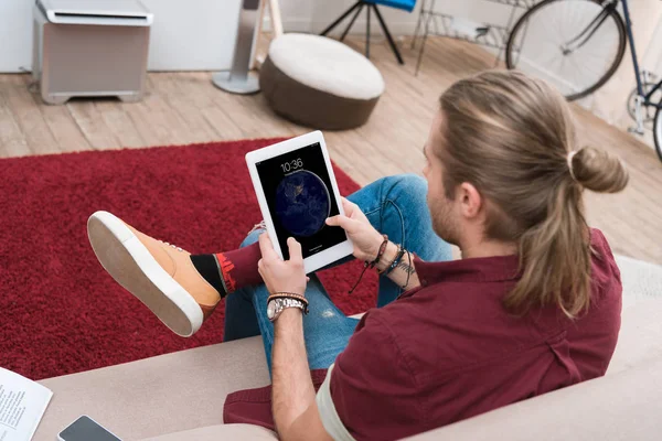 Man sitting on sofa while using ipad tablet — Stock Photo