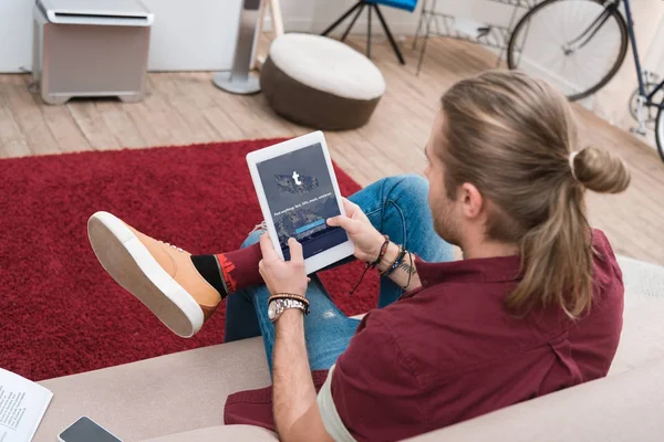 Mann sitzt auf Sofa und benutzt digitales Tablet mit Tumblr-Gerät — Stockfoto