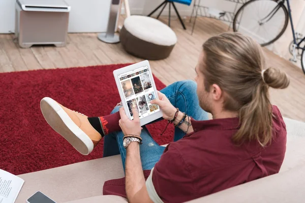 Mann sitzt auf Sofa, während er digitales Tablet mit Pinterest-Gerät benutzt — Stockfoto