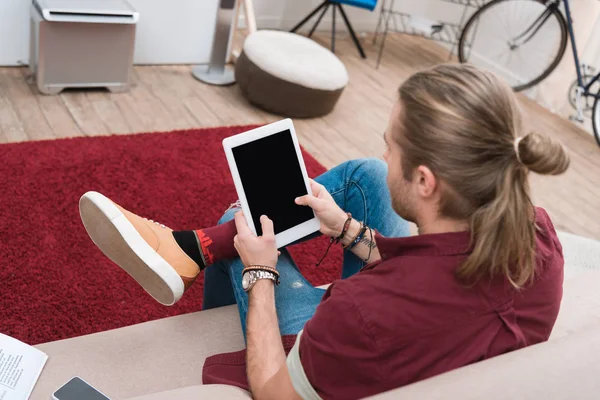 Mann sitzt auf Sofa, während er digitales Tablet mit leerem Bildschirm benutzt — Stockfoto