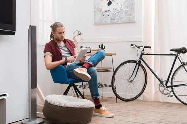 Bel homme utilisant tablette à la maison avec vélo — Photo de stock