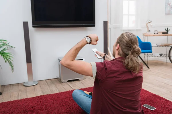 Homem alegre com controle remoto gestos e assistindo tv em casa — Fotografia de Stock