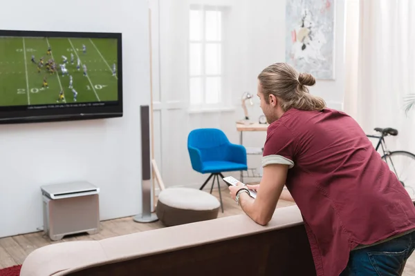 Vue arrière de l'homme regardant le match de football à la maison — Photo de stock