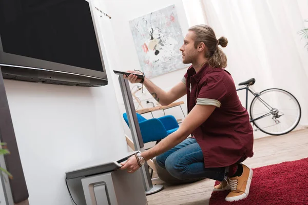 Homem bonito com controle remoto e televisão em casa — Fotografia de Stock