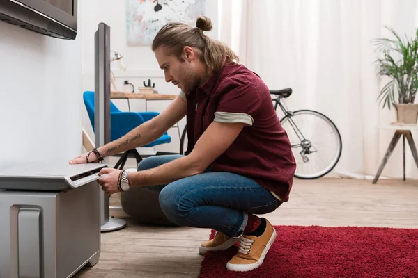 Side view of handsome man tuning television at home — Stock Photo