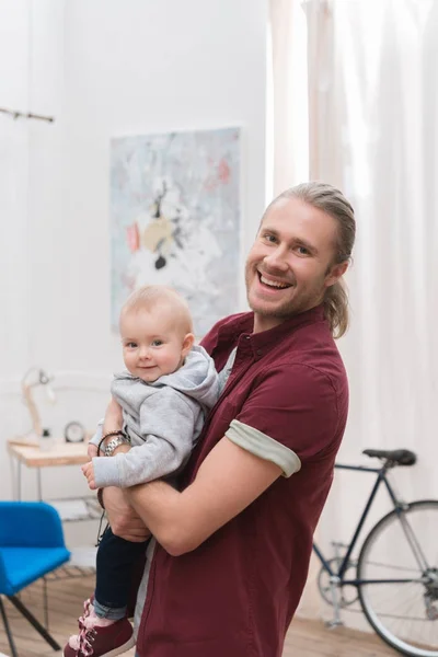 Усміхнений батько тримає свого маленького сина вдома — стокове фото