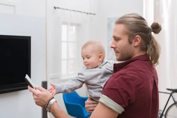 Padre viendo la televisión con el pequeño niño en casa - foto de stock