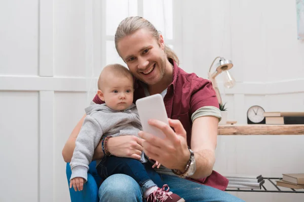 Sorrindo pai tomando selfie com filho adorável em casa — Fotografia de Stock