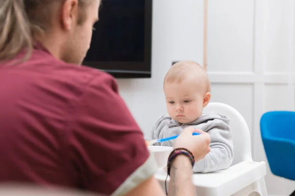 Dad feeding his son with baby food at home — Stock Photo