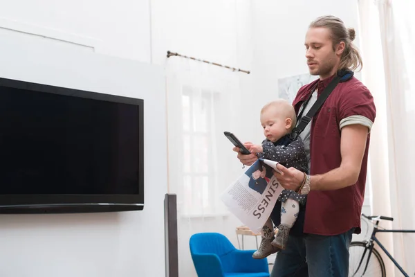 Entzückender Sohn spielt mit Fernbedienung, Vater hält Zeitung in der Hand — Stockfoto