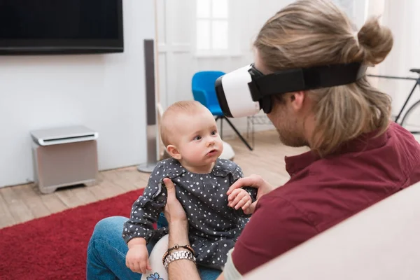 Батько сидить зі своєю маленькою донькою і використовує гарнітуру віртуальної реальності — стокове фото