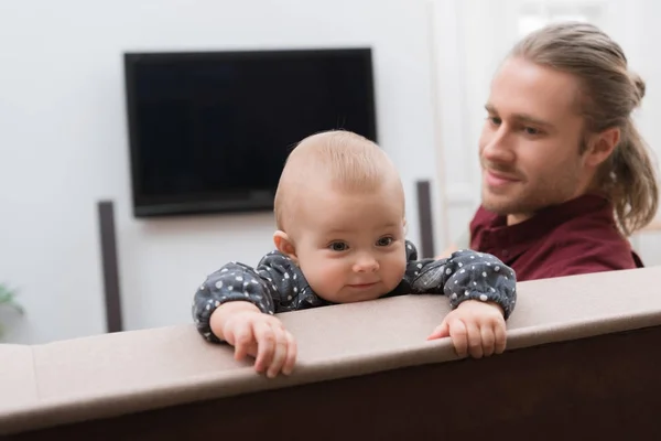 Dad sitting on sofa with his little daughter — Stock Photo