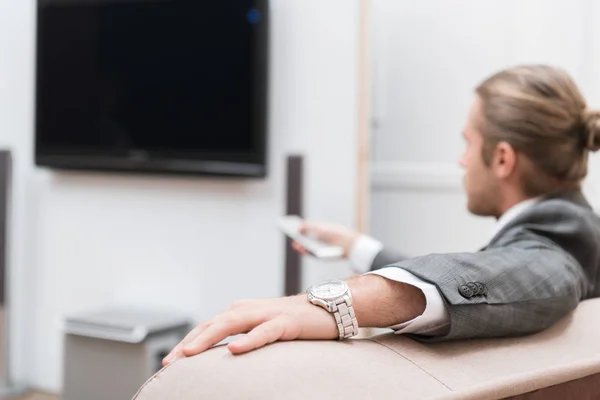 Geschäftsmann sitzt zu Hause und schaltet den Fernseher ein — Stockfoto