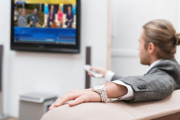 Businessman sitting at home and watching TV — Stock Photo