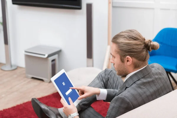 Hombre de negocios usando tableta digital con el sitio web de facebook en casa - foto de stock