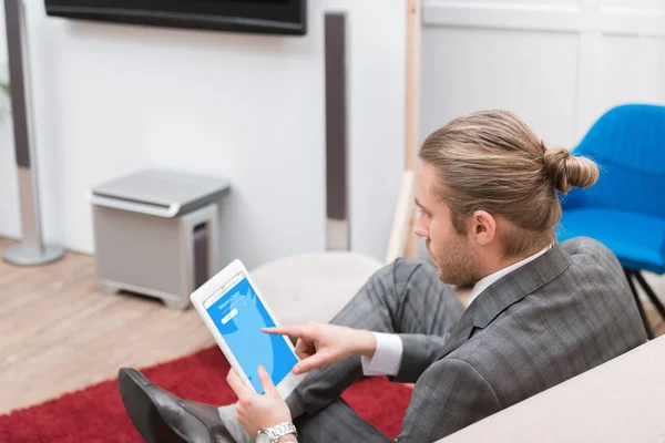 Businessman using digital tablet with twitter website at home — Stock Photo