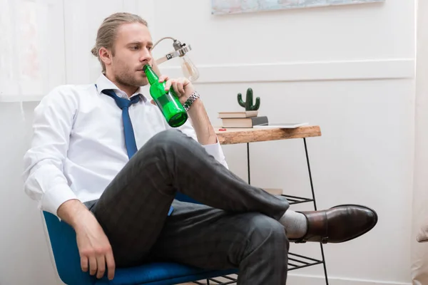 Schöner Mann sitzt in einem Stuhl und trinkt Bier — Stockfoto