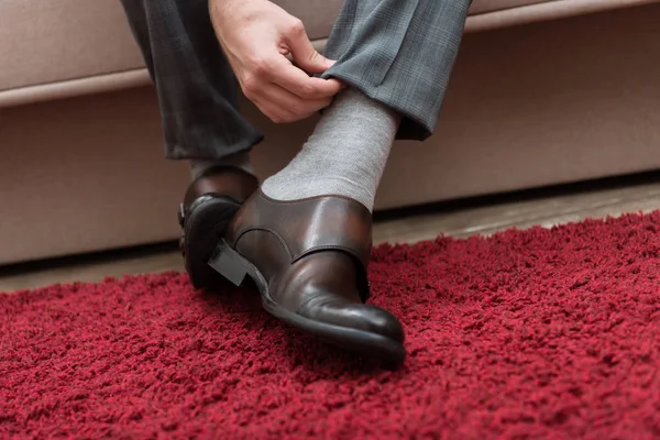 Imagem cortada de homem de negócios fixando calças enquanto sentado em um sofá — Fotografia de Stock