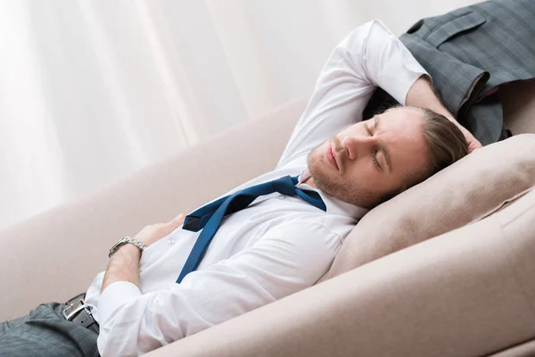 Уставший бизнесмен спит на диване в рубашке и галстуке — стоковое фото