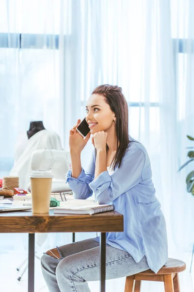 Beautiful designer talking by smartphone at working place — Stock Photo
