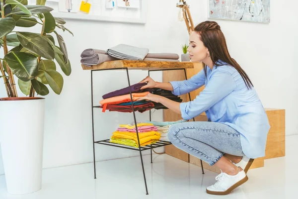 Attraktive Näherin wählt Stoff aus dem Stapel — Stockfoto