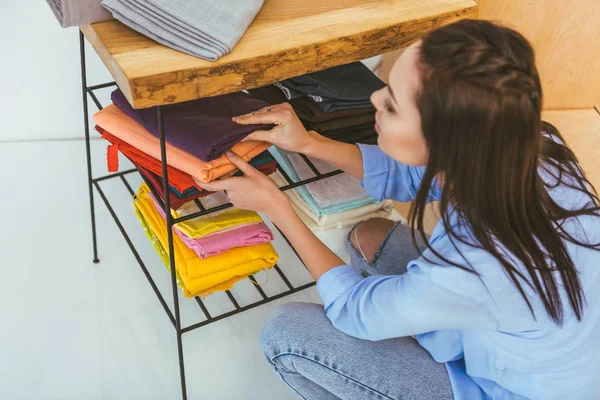 Beautiful seamstress choosing fabric from stack — Stock Photo