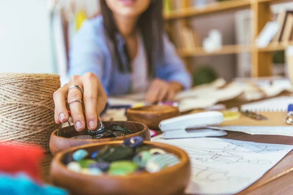 Cropped image of seamstress taking button from wooden bowl — Stock Photo