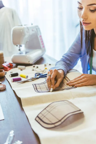 Attractive seamstress marking pattern with piece of chalk — Stock Photo