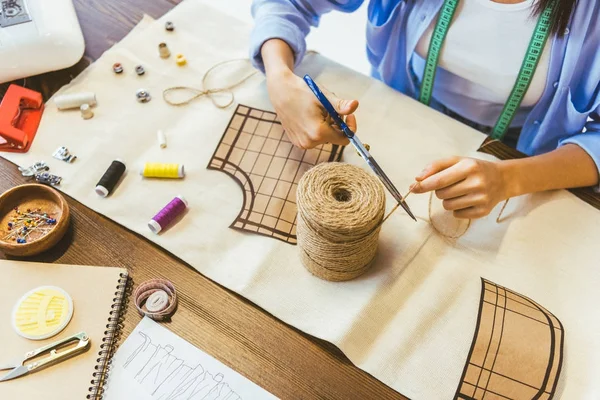 Cropped image of seamstress cutting thread with scissors — Stock Photo